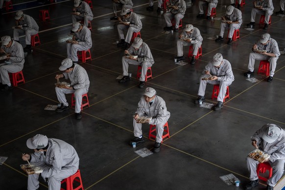 epaselect epa08317268 Workers have lunch while sitting 1.5 meters away from others at the joint-venture Dongfeng Honda in Wuhan, Hubei province, China, 23 March 2020 (issued 24 March 2020). The automa ...