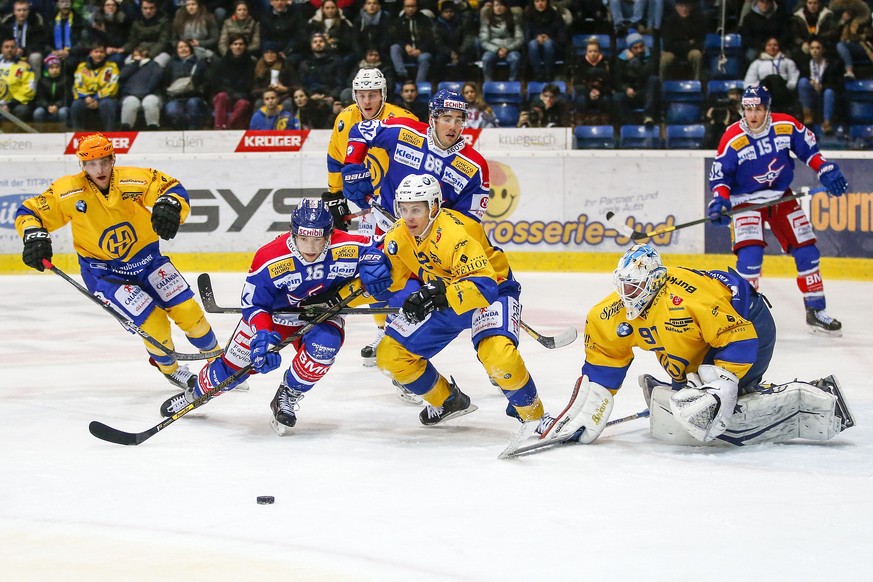 EHC Kloten Stuermer Daniele Grassi, Mitte links, gegen HC Davos Verteidiger Felicien DuBois, Mitte rechts, und Torhueter Gilles Senn waehrend dem Eishockey-Meisterschaftsspiel der National League A zw ...