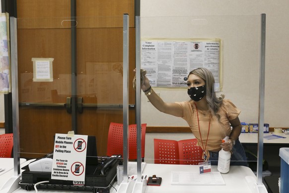 Cameron County early voting clerk Crystal Garcia sanitizes the plastic shields for the poll worker&#039;s station Thursday, Oct. 15, 2020, before the early voting polling location opens in Brownsville ...