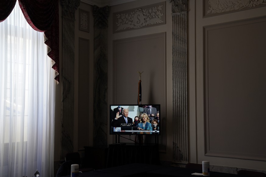 A television displays Joe Biden being sworn in as the 46th president of the United States by Chief Justice John Roberts as Jill Biden holds the Bible during the 59th Presidential Inauguration at the U ...