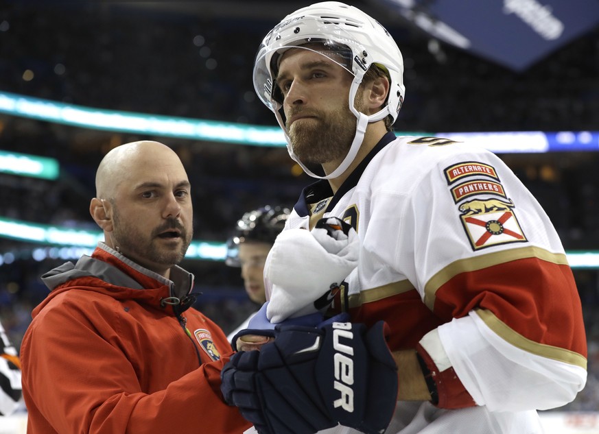 Florida Panthers defenseman Aaron Ekblad is looked at by a trainer after getting checked into the boards by Tampa Bay Lightning center Gabriel Dumont during the second period of an NHL hockey game, Sa ...