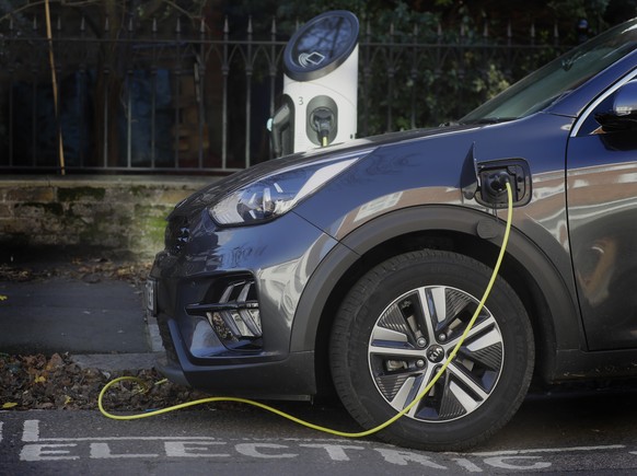 An electric car charges on a street charging port in London, Wednesday, Nov. 18, 2020. Britain says it will ban the sale of new gasoline and diesel cars by 2030, a decade earlier than its previous com ...