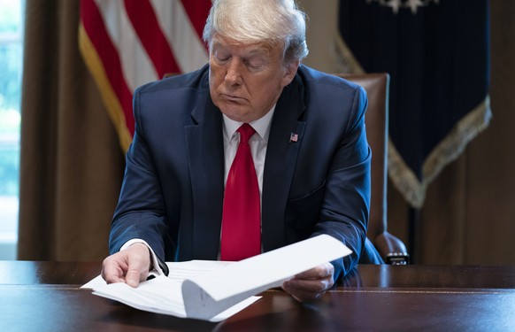 President Donald Trump looks at his notes during a meeting with people that have recovered from COVID-19, in the Cabinet Room of the White House, Tuesday, April 14, 2020, in Washington. (AP Photo/Evan ...