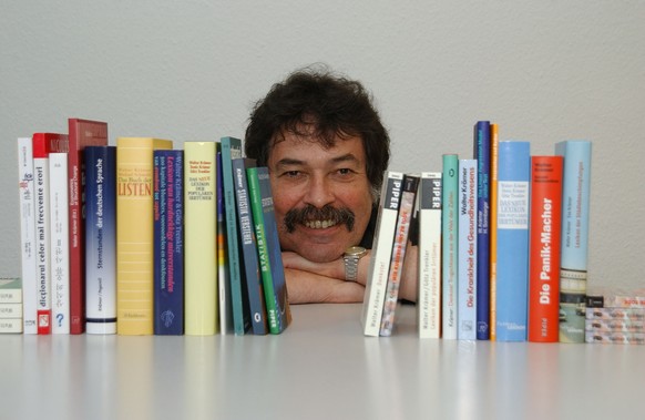 Walter Krämer zwischen seinen von ihm geschriebenen Büchern.