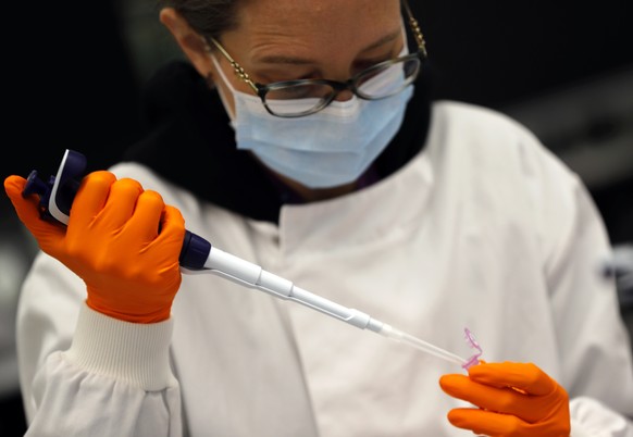 A lab assistant uses a pipette to prepare Coronavirus RNA for sequencing at the Wellcome Sanger Institute that is operated by Genome Research in Cambridge, Thursday, March 4, 2021. Cambridge Universit ...