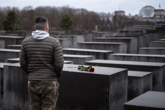 A young man stands in front of the Holocaust Memorial after he laid down a red rose on a slab of the memorial to commemorate the victims of the Nazis in Berlin, Sunday, Jan. 27, 2019. The Internationa ...