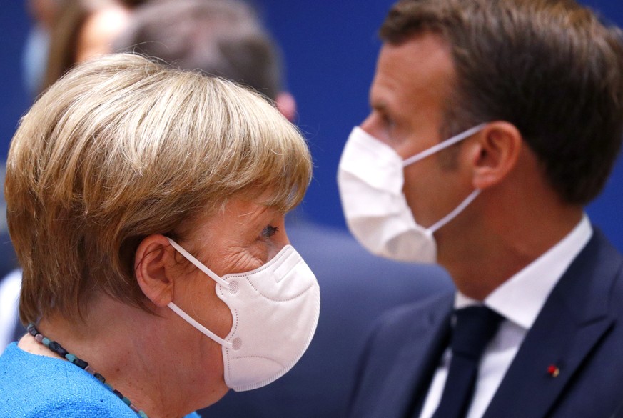epa08553186 German Chancellor Angela Merkel (L) and France&#039;s President Emmanuel Macron (R), both wearing a face mask, at the start of the second day of an EU summit in Brussels, Belgium, 18 July  ...