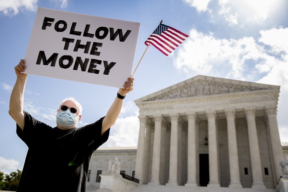 Bill Christeson holds up a sign that reads &quot;Follow the Money&quot; outside the Supreme Court, Thursday, July 9, 2020, in Washington. The Supreme Court ruled Thursday that the Manhattan district a ...