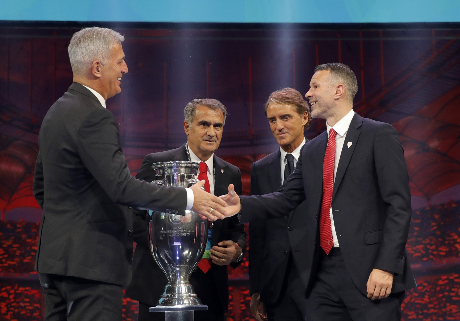 The coaches of Switzerland Vladimir Petkovic, left, Turkey Senol Gunes, second left, Italy Roberto Mancini, second right, and Wales Ryan Giggs who will play in group A, pose with the trophy after the  ...