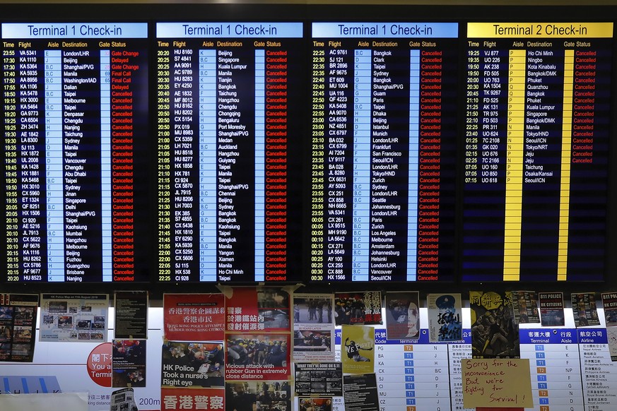 Protest placards are placed as the flights information board shows the cancellation of outbound flights at the Hong Kong International Airport, Monday, Aug. 12, 2019. One of the world&#039;s busiest a ...