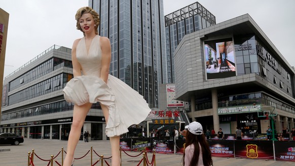 A woman take pictures with a mobile phone of a giant statue of Marilyn Monroe standing near a shopping mall in Changzhou, Jiangsu Province, China, May 7, 2016. REUTERS/Stringer ATTENTION EDITORS - THI ...