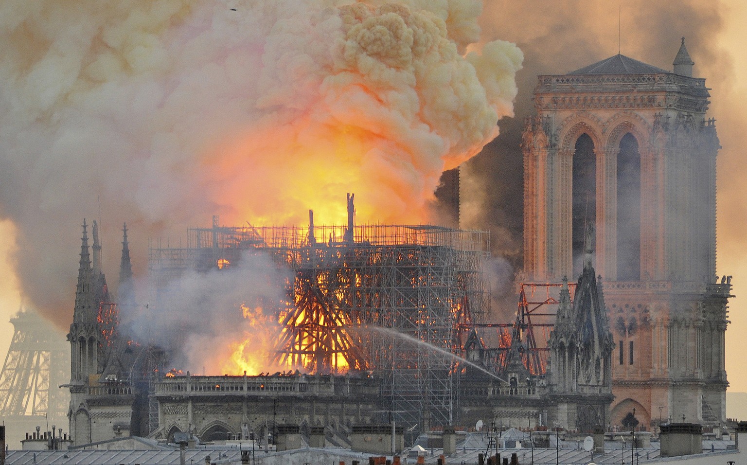 In this image made available on Tuesday April 16, 2019 flames and smoke rise from the blaze after the spired toppled over on Notre Dame cathedral in Paris, Monday, April 15, 2019. An inferno that rage ...