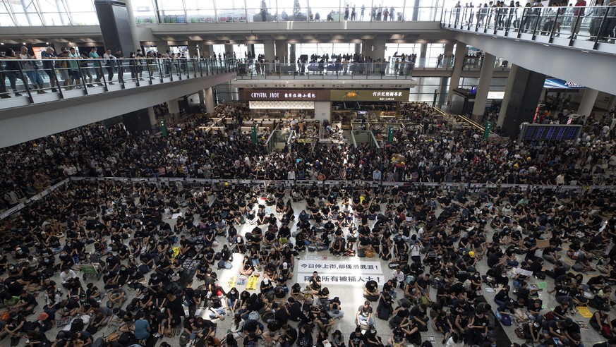 Protesters surround banners that read &quot;Those charge to the street on today is brave!,&quot; center top, and &quot;Release all the detainees!&quot; during a sit-in rally at the arrival hall of the ...
