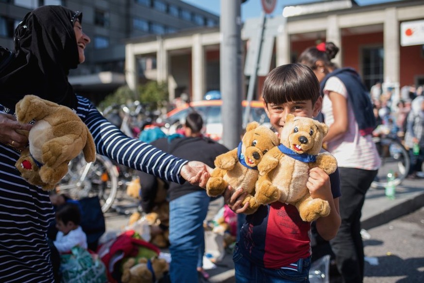 Kinder werden in München mit Teddybären empfangen.