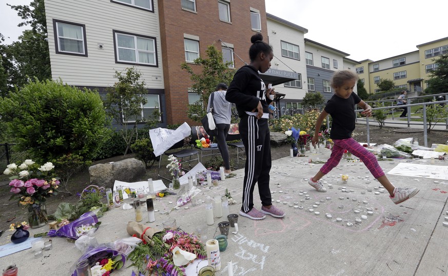 A child steps over burned-out candles at a memorial outside where a pregnant mother was shot and killed at her apartment a day earlier by police, Monday, June 19, 2017, in Seattle. Family members of C ...