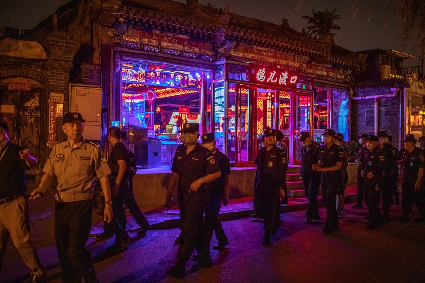 epa08473451 A policeman and security men patrol the area near the Houhai lake as they check bars and look for street vendors, in Beijing, China, 08 June 2020. The nationwide lockdown during the COVID- ...