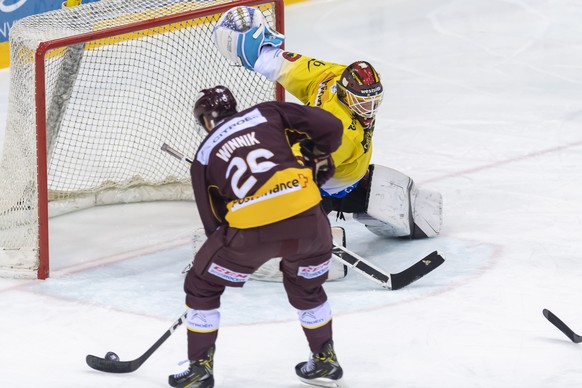 Le gardien du club bernois, Tomi Karhunen, droite, a la lutte pour le puck avec le joueur du club genevois, Daniel Winnik, gauche, lors du match du championnat suisse de hockey sur glace de National L ...