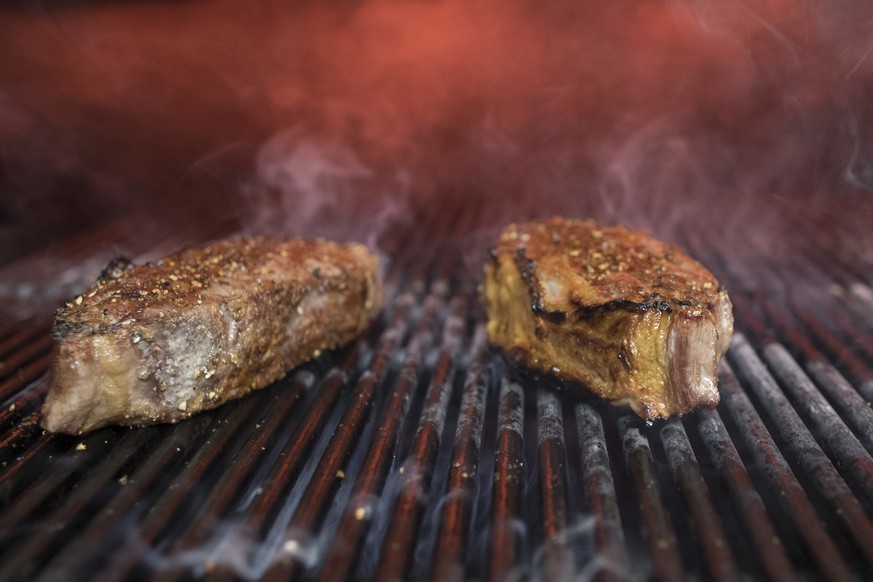 FILE - This Nov. 27, 2018 file photo shows steaks on a grill at a restaurant in New York. The idea behind the low-carb diet is that the body enters a ketogenic, fat-burning state when it runs out of t ...