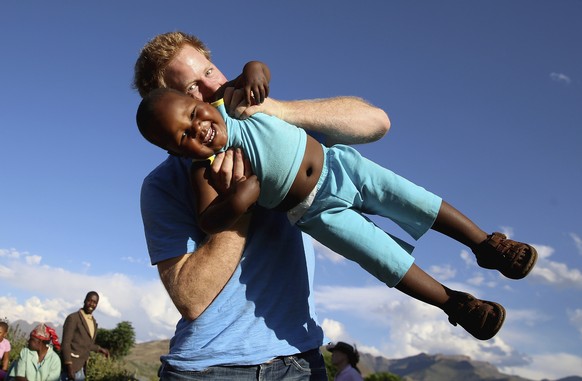 FILE - In this file photo taken on Dec. 6 2014, Britain&#039;s Prince Harry swings young three year old orphan boy Lerato in this photograph taken with the help of a three year old blind girl called K ...