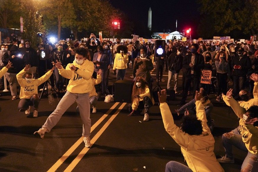 A dance group entertains people gathered outside the White House while awaiting election results, Tuesday, Nov. 3, 2020, in Washington. (AP Photo/John Minchillo)