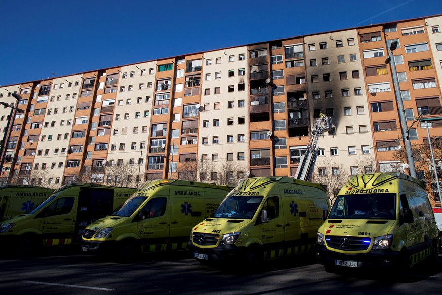 epa07263236 Ambulances are seen as firefighters work after extinguishing a fire in a block of flats in Badalona, Barcelona, Spain, 05 January 2019. Three people died and 15 others were injured, includ ...