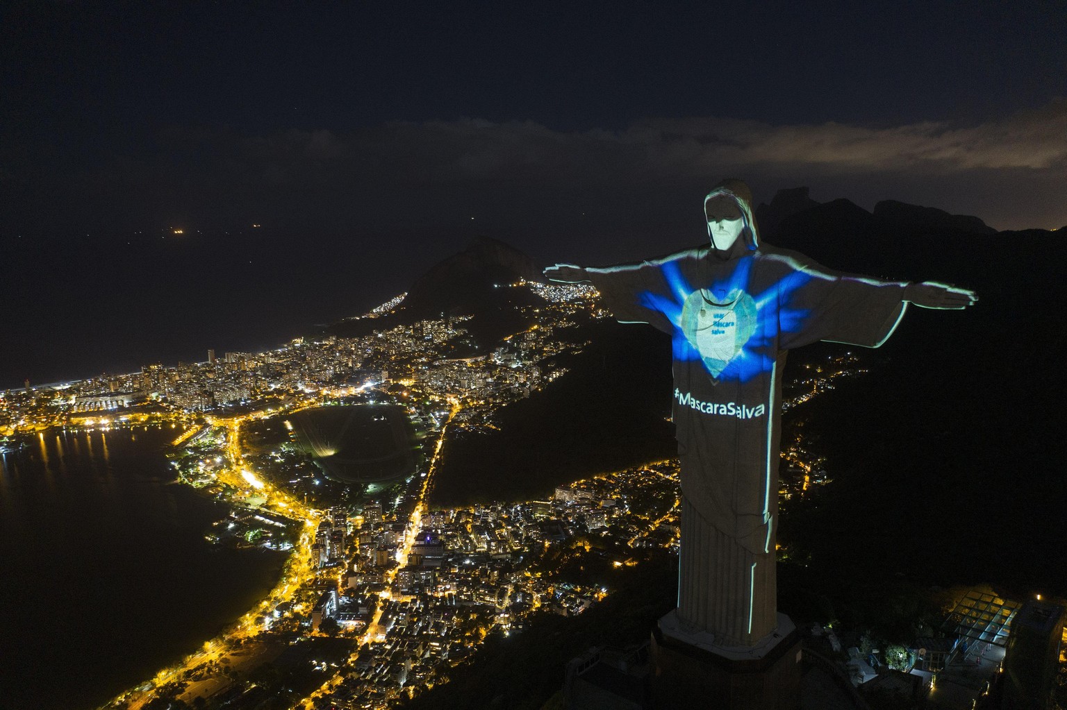 In this Sunday, May 3, 2020 photo, the iconic Christ the Redeemer statue is lit up as if wearing a protective mask and with a hashtag that reads in Portuguese: &quot;Mask saves,&quot; amid the new cor ...