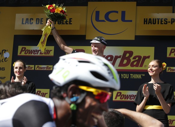 Eritreas Daniel Teklehaimanot, foreground, is all smiles as he passes his teammate and stage winner Britains Stephen Cummings who celebrates his victory on the podium after the seventh stage of the  ...