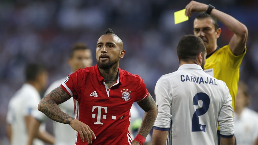 Referee Viktor Kassai of Hungary shows a yellow card to Bayern&#039;s Arturo Vidal, left, during the Champions League quarterfinal second leg soccer match between Real Madrid and Bayern Munich at Sant ...