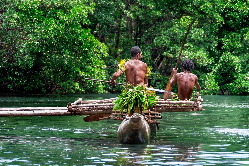 Zwei indigene Stammesmänner paddeln in einem traditionellen Kanu in der Nähe von Tufi auf Papua-Neuguinea.