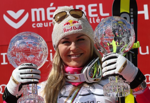 Lindsey Vonn, of the United States, holds the alpine ski, women&#039;s World Cup super-G and downhill&#039;s disciplines trophies as she celebrates on the podium, at the World Cup finals in Meribel, F ...