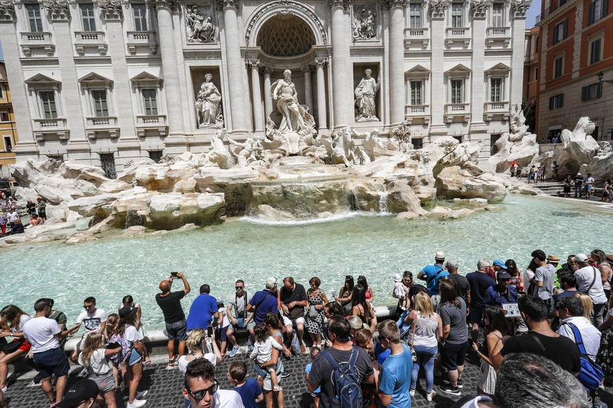 epa06887919 Tourists are seen next to the world-famous Trevi Fountain during a hot and muggy day in Rome, Italy, 14 July 2018. The Italian Health Ministry issued on 13 July, a heat alert for eight Ita ...