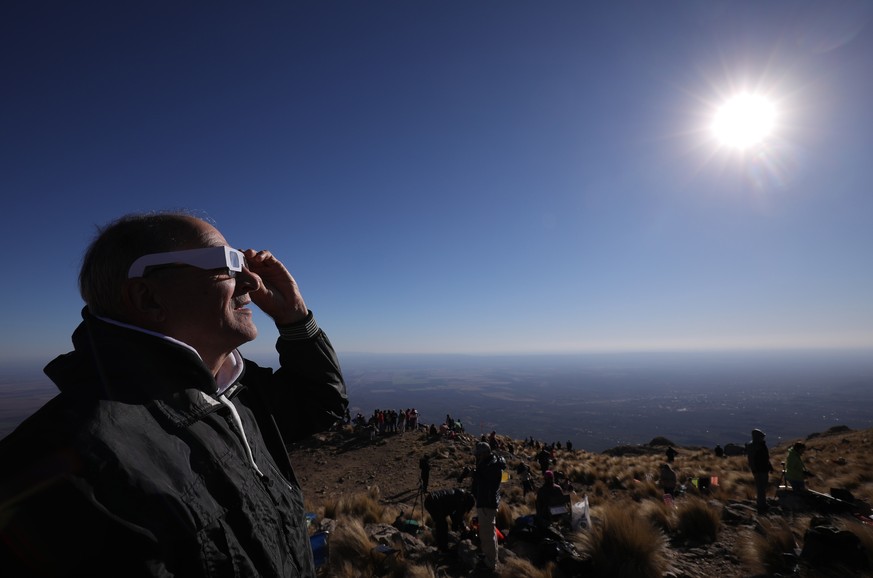 epa07690617 A man looks at the sun with special glasses before the total solar eclipse, in Merlo, San Luis, Argentina, 02 July 2019. A total solar eclipse will cross above Chile and Argentina, as well ...