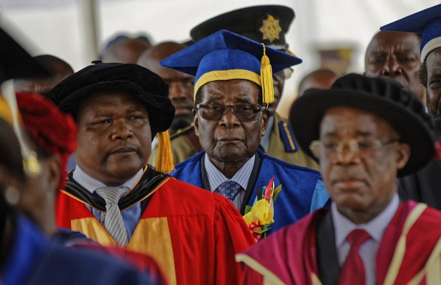 Zimbabwe&#039;s President Robert Mugabe, center, arrives to preside over a student graduation ceremony at Zimbabwe Open University on the outskirts of Harare, Zimbabwe Friday, Nov. 17, 2017. Mugabe is ...