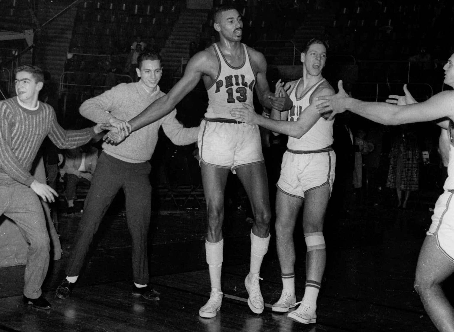 FILE -- Wilt Chamberlain (13) of the Philadelphia Warriors, is congratulated by unidentified teammates and fans who rushed onto the floor in Hershey, Pa., after Chamberlain scored his 100th points for ...