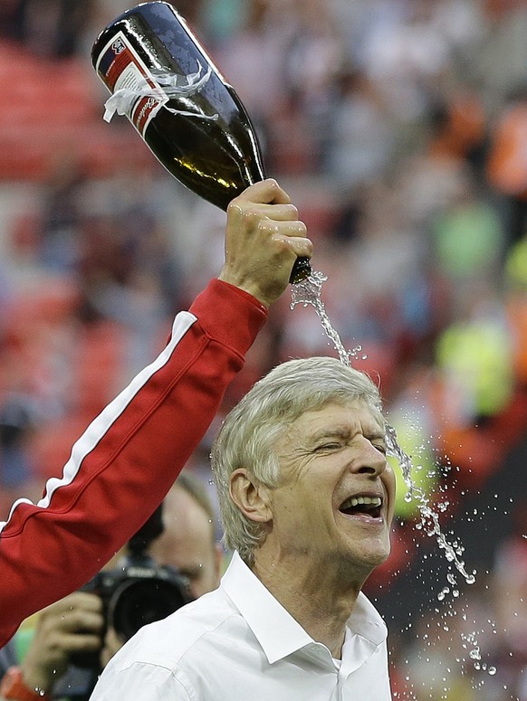 FILE - In this Saturday, May 17, 2014 file photo Arsenal&#039;s coach Arsene Wenger is doused with champagne by his players as they celebrate after winning the English FA Cup final soccer match betwee ...