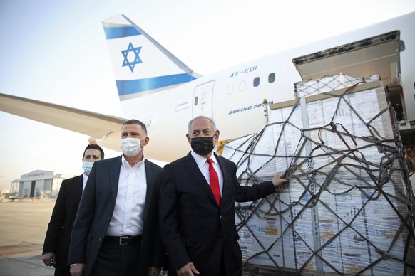 Israel Prime Minister Benjamin Netanyahu, center, and his Health Minister Yuli Edelstein, second left, attend the arrival of plane with a shipment of Pfizer coronavirus vaccines, at Ben Gurion Airport ...