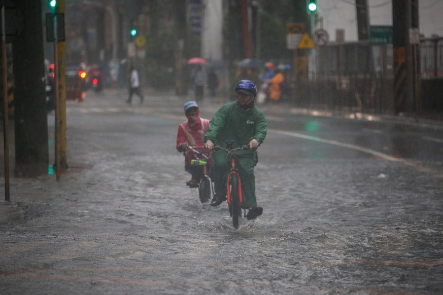 epa09356324 Food delivery riders transit through a flooded road during downpour in Makati, Metro Manila, Philippines, 21 July 2021. The Philippine weather bureau said that monsoon rains will continue  ...