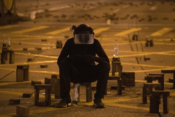 A protester sit with brick obstacles and Molotov cocktail on a barricade road near the the Hong Kong Polytechnic University campus in Hong Kong on Thursday, Nov. 14, 2019. Hong Kong police warned prot ...