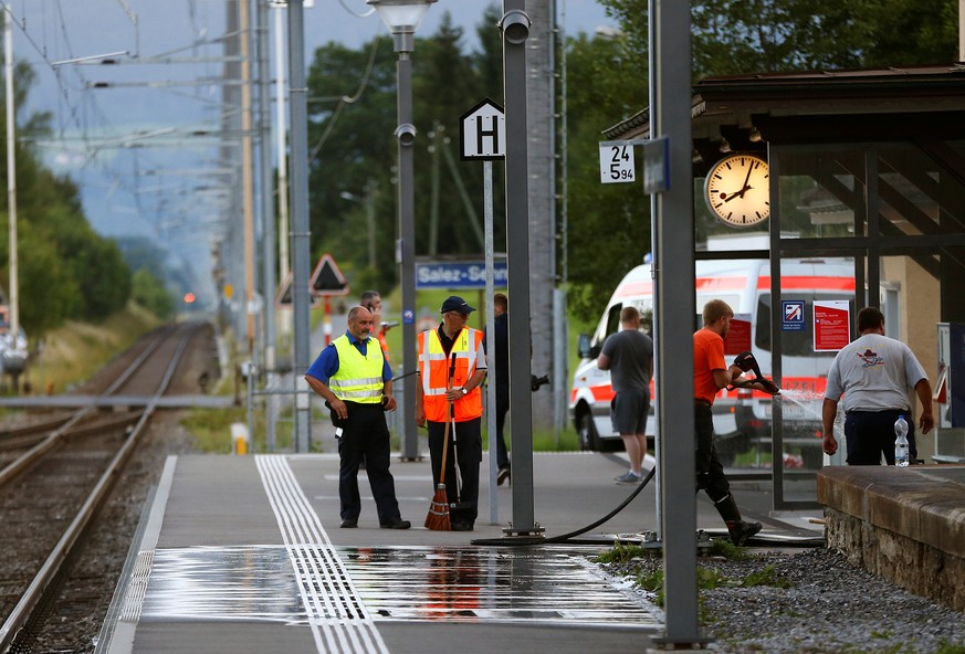 A Swiss police officer stands near workers cleaning a platform after a 27-year-old Swiss man&#039;s attack on a Swiss train at the railway station in the town of Salez, Switzerland August 13, 2016. RE ...