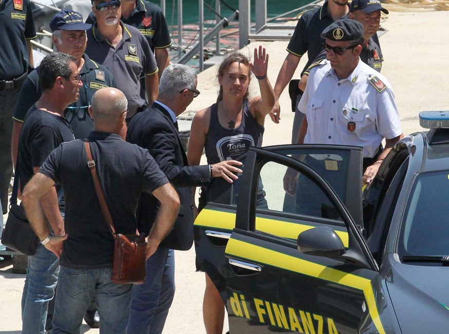 Sea-Watch 3 captain Carola Rackete, center, from Germany, waves as she arrives in the Sicilian port of Porto Empedocle, escorted by Italian finance police, from Lampedusa, Italy, Monday, July 1, 2019. ...