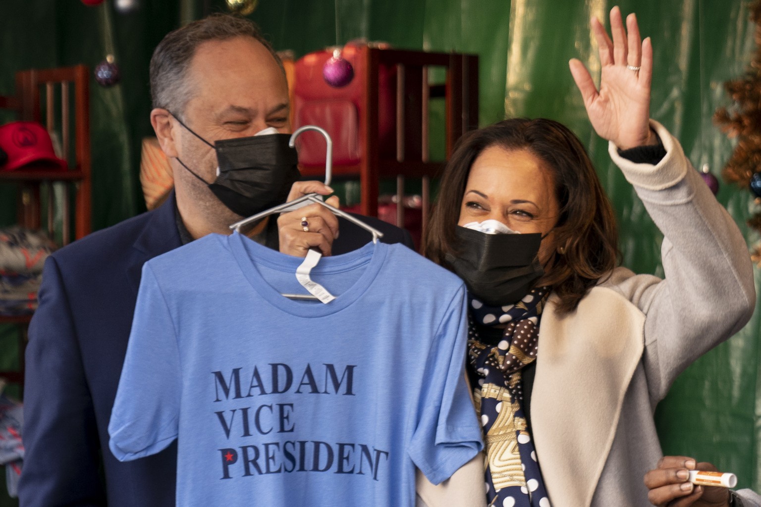 Vice President-elect Kamala Harris, accompanied by her husband Doug Emhoff, left, holds up a shirt that reads &quot;Madam Vice President&quot; as they visit the &quot;made in DC&quot; booth in the Dow ...