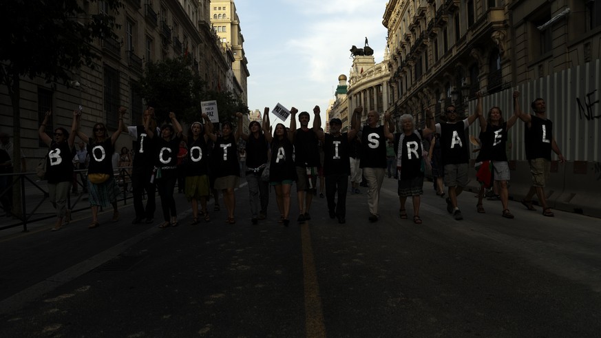 People march on the streets, displaying T-shirts reading &#039; Boycot Israel&#039; as they shout anti Israeli slogans, during a protest against the Israeli airstrikes of the Gaza strip, in Madrid, Sp ...