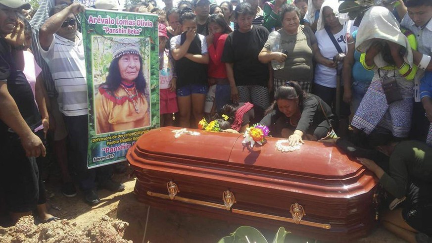 In this Sunday, April 22, 2018 photo, people cry over the coffin of plant healer Olivia Arevalo during her burial in Ucayali, Peru. Authorities say a mob dragged Canadian man Sebastian Woodroffe by th ...