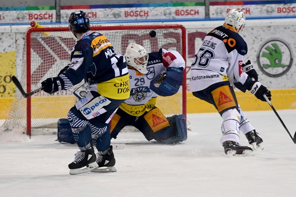 From left, Ambri&#039;s player Marco Mueller, Zug&#039;s goalkeeper Sandro Aeschlimann and Zug&#039;s player Timo Helbling, during the preliminary, round game of National League A (NLA, LNA) Swiss Cha ...