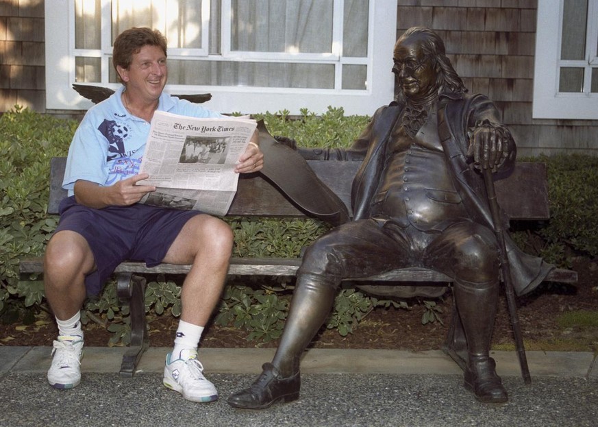 Roy Hodgson, Trainer der Schweizer Fussballnationalmannschaft, liest am 27. Juni 1994 in Palo Alto, Kalifornien auf einer Sitzbank mit einer Statue von Benjamin Franklin die Zeitung &quot;The New York ...
