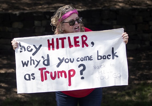 epa07717335 A woman protests as the motorcade transporting US President Donald J. Trump leaves at the Trump National Golf in Sterling, Virginia, USA,14 July 2019. EPA/ERIK S. LESSER / POOL