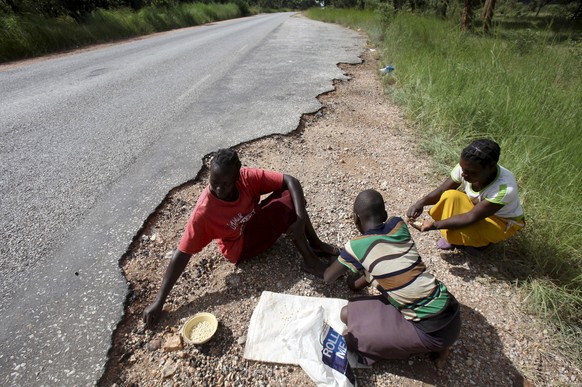 Grosse Hungersnot: Kinder lesen Weizenkörner auf, die ein Lastwagen in Simbabwe verloren hat.