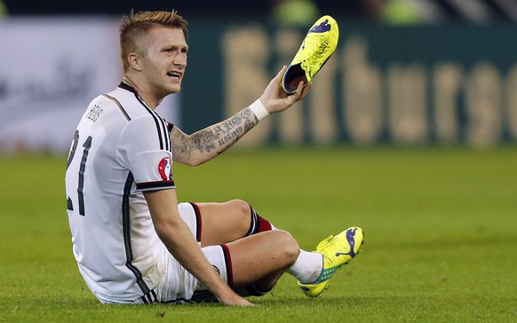 Germany’s Marco Reus shows his lost shoe during the Euro 2016 soccer qualifying group D match between Germany and Scotland in Dortmund, Germany, Sunday, Sept. 7, 2014. (AP Photo/Frank Augstein)