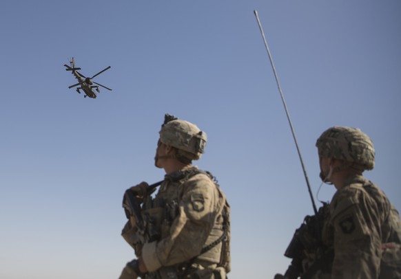 This June 10, 2017 photo released by the U.S. Marine Corpsshows an AH-64 Apache attack helicopter provides security from above while CH-47 Chinooks drop off supplies to U.S. Soldiers with Task Force I ...