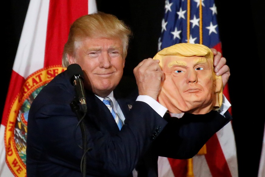 Republican presidential nominee Donald Trump holds up a mask of himself as he speaks during a campaign rally in Sarasota, Florida, U.S. November 7, 2016. REUTERS/Carlo Allegri TPX IMAGES OF THE DAY